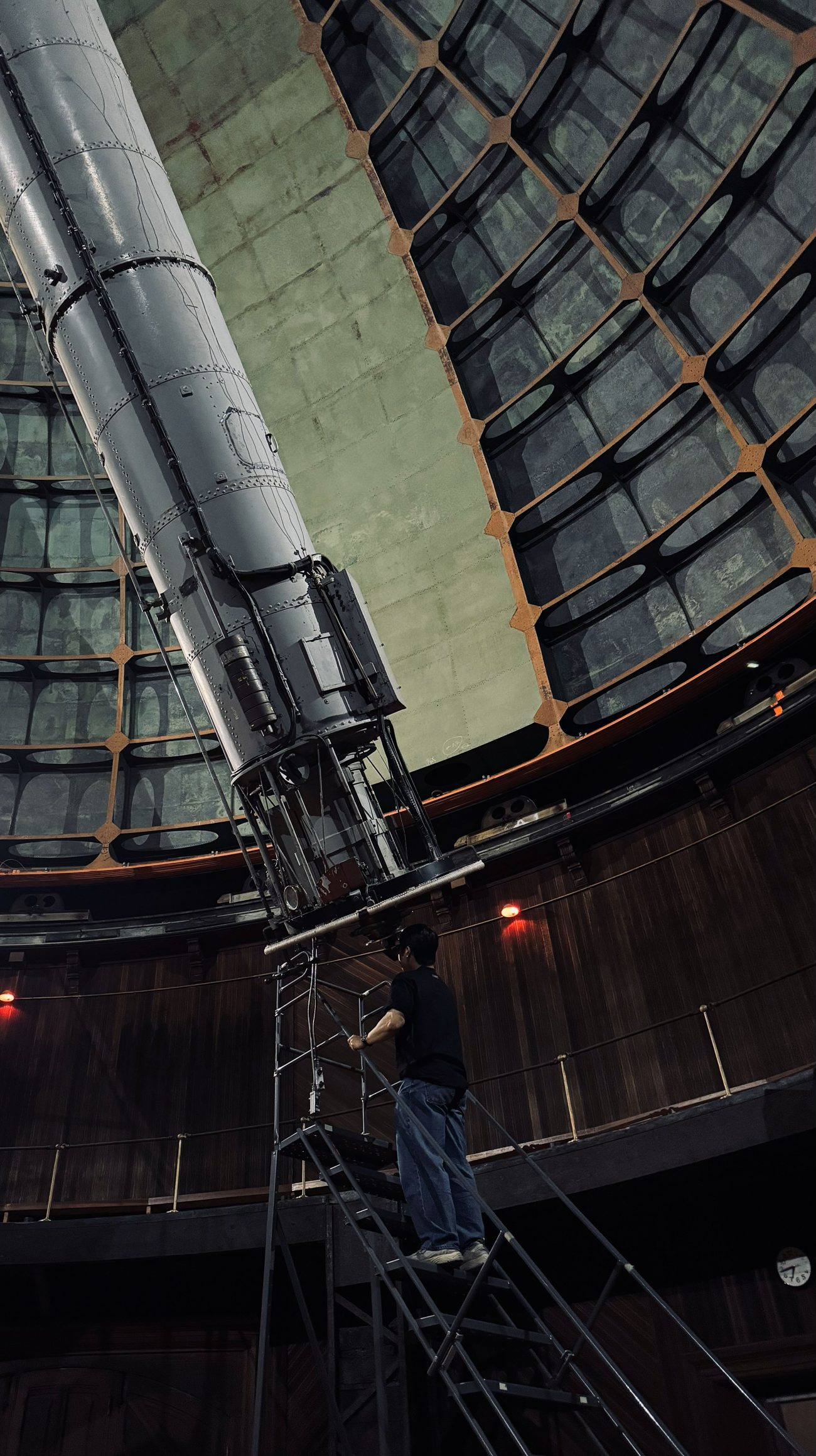 Minjae Kim on the observing ladder beside a large refracting telescope inside the Lick Observatory dome